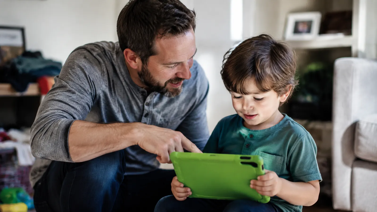 Parent and kindergarten-age child looking together at a LeapFrog LeapPad screen showing a reading progress chart